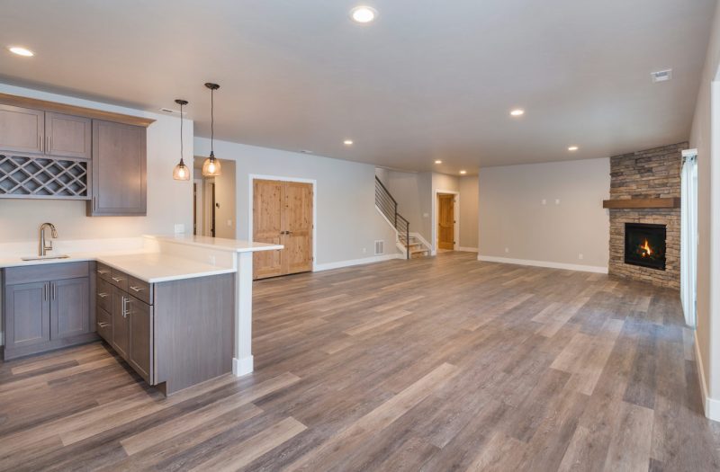 View of a contemporary basement featuring dark wood flooring with a TV and fireplace setup, illustrating a sleek design upgrade.
