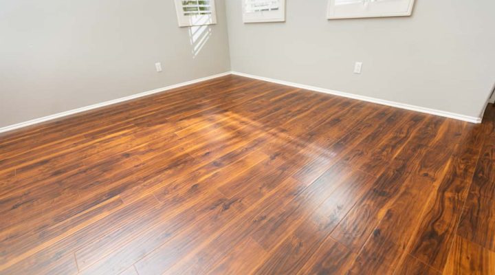 A complete installation of glossy dark wood flooring in a room with natural sunlight reflecting, showcasing the rich texture and color of the wood.
